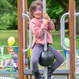 Girl climbing a ball climber onto the deck of a multi play unit